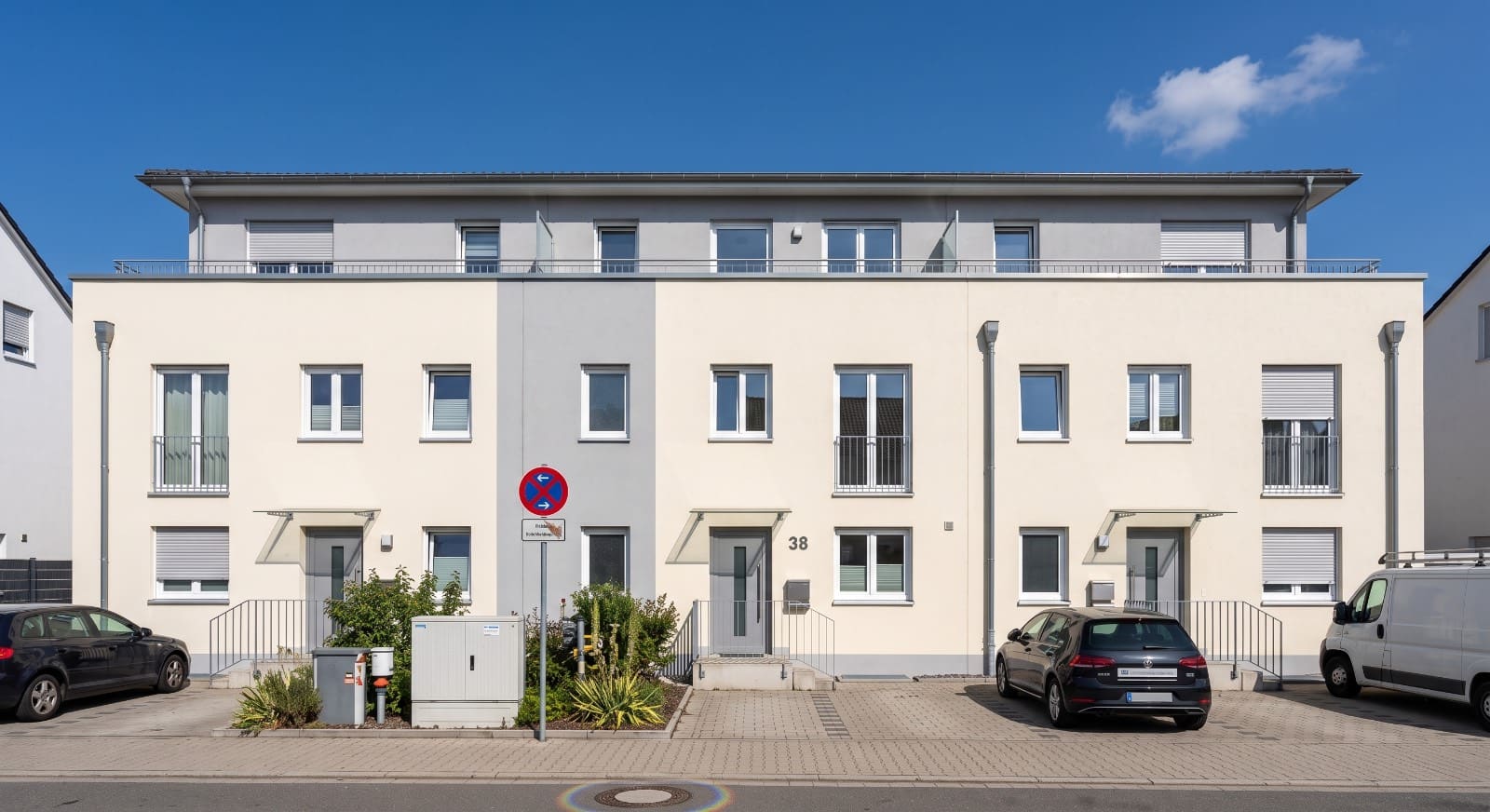 Frontansicht eines gepflegten Mehrfamilienhauses mit heller Fassade und zurückgesetztem Dachgeschoss aus dem eigenen Bestand