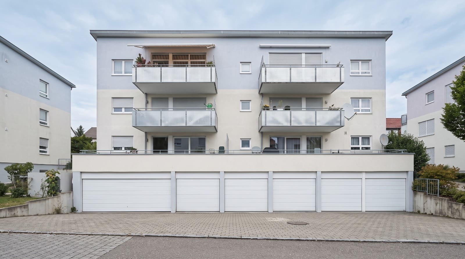 Rückansicht des Mehrfamilienhauses mit Balkonen und vorgelagerter Garagenzeile